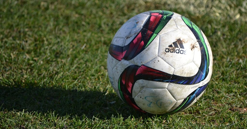 privacy policy Vibrant soccer ball resting on a lush green field under natural sunlight.