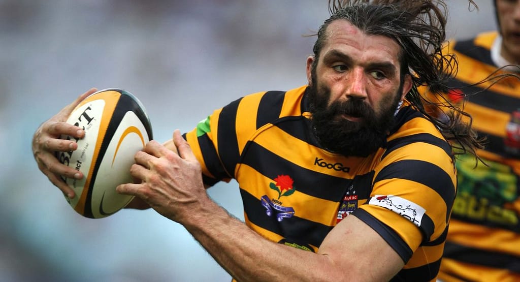 "Benjie Bougas Rugby action shot, showcasing agility and determination as he evades a tackle while sprinting forward with the ball."