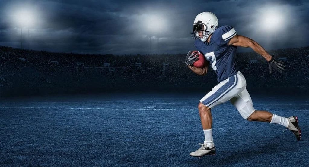 "A visually striking image of an American football player in mid-air, fully extended to catch a football. He wears a navy blue jersey with the number 7, a helmet with a dark visor, gloves, and white football pants with blue stripes. The background features a large stadium with empty seats beneath a dramatic cloudy sky, capturing the intensity and athleticism of the moment. This image represents the essence of an 'American football persona poem,' symbolizing determination, skill, and the spirit of the game. Coach American Football Persona Poem