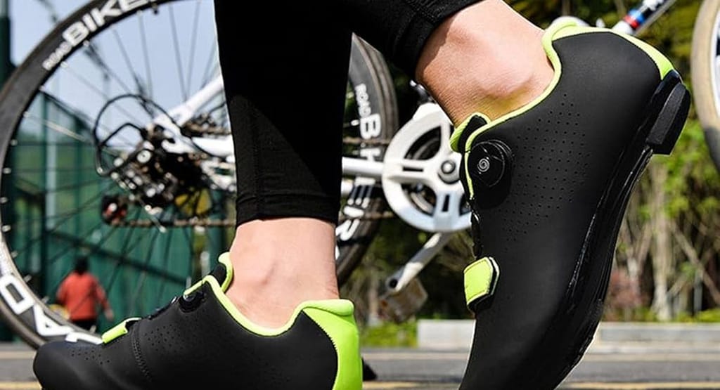 A close-up of a cyclist's foot wearing high-performance white cycling shoes with dial fasteners, clipped into the pedal of a road bike. The background features a blurred bicycle wheel and a sunlit outdoor setting, emphasizing the sport of cycling and professional gear."
Let me know if you'd like any modifications!