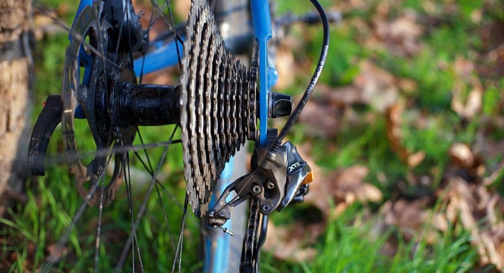 "Close-up of an old bicycle gear shifting mechanism, showcasing the chain, crankset, and derailleur components. A simple guide to mastering your bike’s gears can help optimize shifting performance for smoother rides." Fix Bike Ghost Shifting
