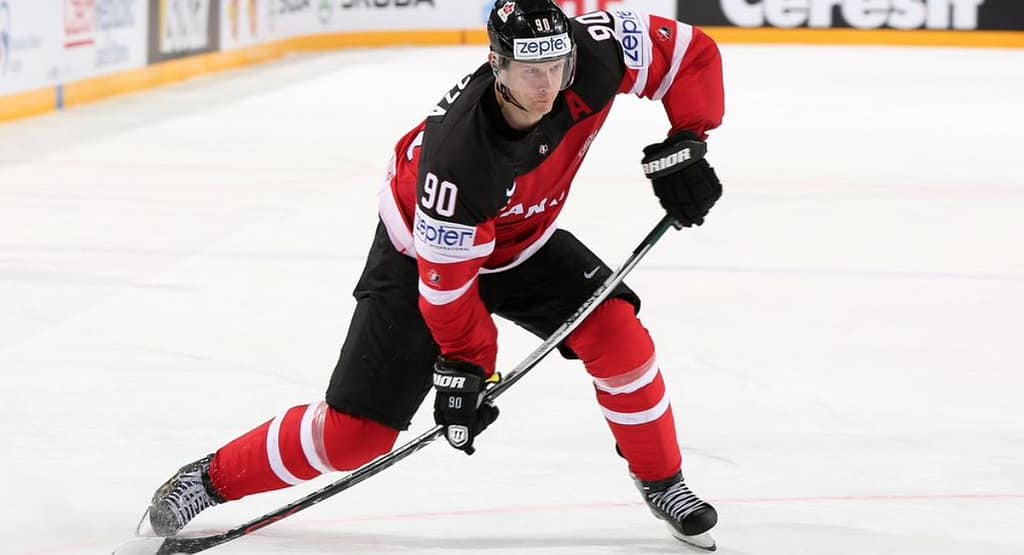 Action shot from a professional ice hockey game showing players in motion. While the image features teams in black and white/red jerseys, it does not depict the classic Chiefs hockey jersey made famous by the fictional Charlestown Chiefs from Slap Shot. The Chiefs jersey typically features blue and gold striping with bold "Chiefs" lettering across the chest