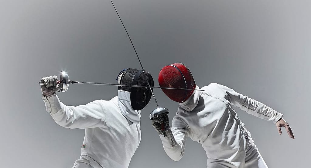 "Two fencers in mid-action during a high-speed bout, each demonstrating precise timing and explosive movement. One fencer lunges forward while the other parries with agile footwork and blade control showcasing the critical role of tempo and timing in competitive fencing."