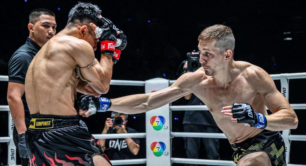 "Muay Thai practitioners wearing colored Pra Jiad armbands—white, yellow, green, blue, red, and black—symbolizing progression in Western-adapted ranking systems, standing in a gym setting."