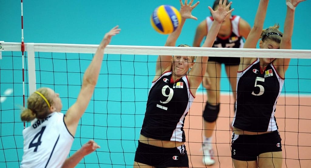 Jacqueline Opheim lunges low to dig a volleyball mid-play, showcasing intense focus, agility, and defensive skill on a professional indoor court.