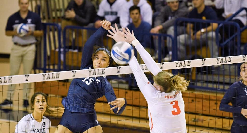 Jacqueline Opheim lunges low to dig a volleyball mid-play, showcasing intense focus, agility, and defensive skill on a professional indoor court.